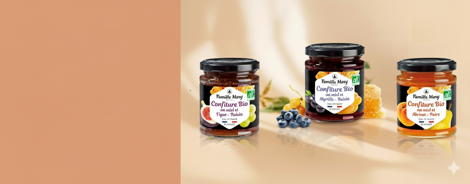 Trois pots de confiture bio de la marque Famille Mary (figue-raisin, myrtille-raisin, abricot-poire) sont présentés sur un fond dégradé pêche, avec des fruits frais et du miel autour, et un espace de couleur unie à gauche.